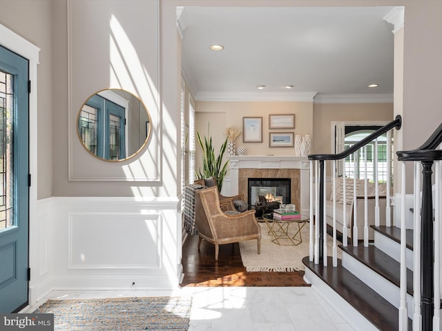 entryway with crown molding, recessed lighting, a glass covered fireplace, and stairs