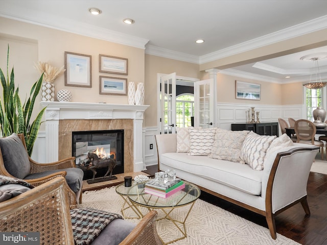 living room featuring crown molding, a premium fireplace, wood finished floors, and a decorative wall