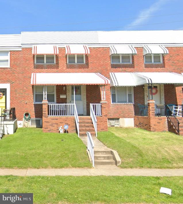 view of property with a porch, a front lawn, and brick siding