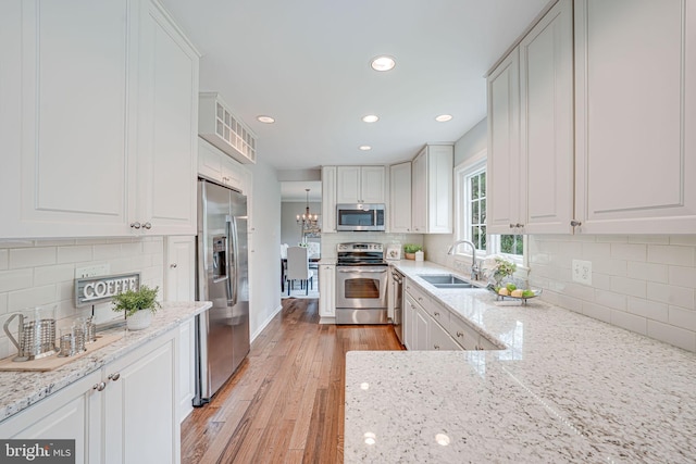 kitchen with recessed lighting, a sink, light wood-style flooring, backsplash, and stainless steel appliances