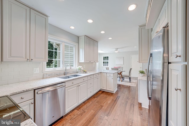 kitchen featuring a sink, stainless steel appliances, recessed lighting, light wood-type flooring, and tasteful backsplash