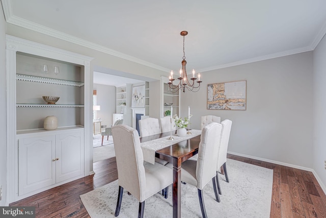 dining room with an inviting chandelier, crown molding, built in features, baseboards, and dark wood-style floors
