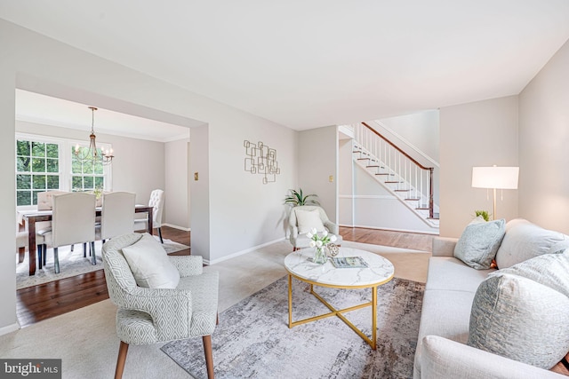 carpeted living room with stairs, baseboards, and an inviting chandelier