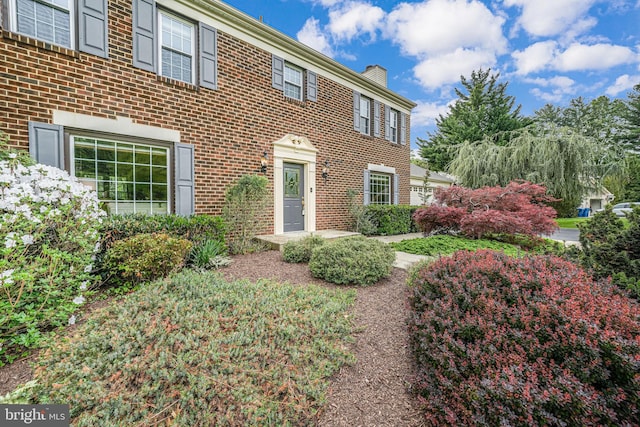 colonial inspired home with brick siding and a chimney