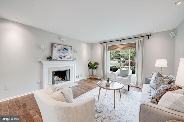 living area with visible vents, wood finished floors, baseboards, recessed lighting, and a high end fireplace