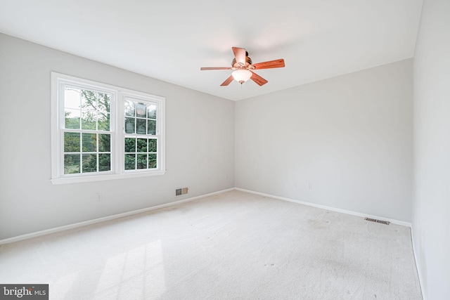 carpeted empty room featuring ceiling fan, visible vents, and baseboards