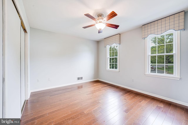 empty room featuring visible vents, wood-type flooring, baseboards, and a healthy amount of sunlight