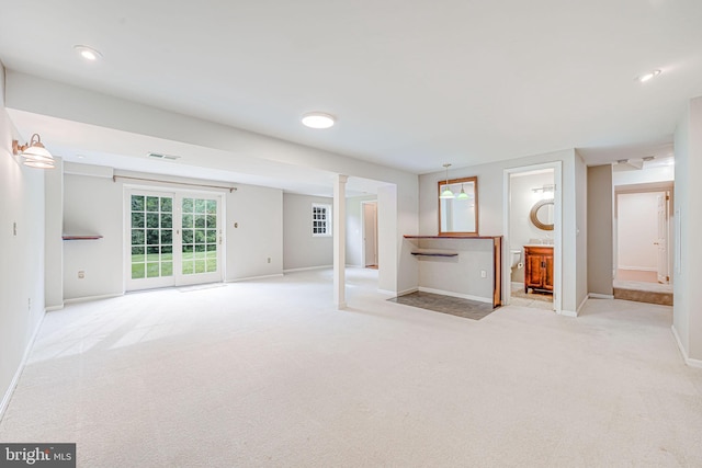unfurnished living room featuring baseboards, light colored carpet, and visible vents