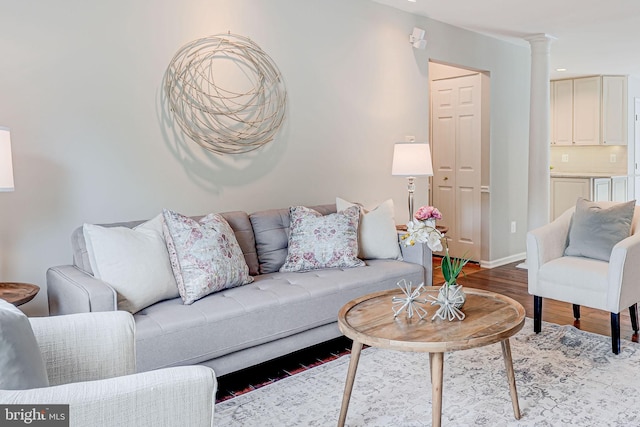 living area featuring ornate columns, recessed lighting, light wood-style flooring, and baseboards