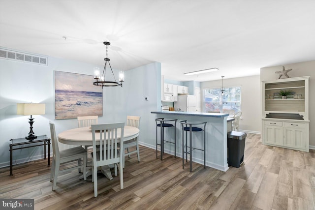 dining space with visible vents, light wood finished floors, and a notable chandelier