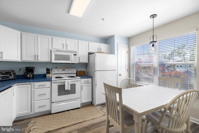 kitchen featuring dark countertops, white appliances, white cabinetry, wood finished floors, and a toaster
