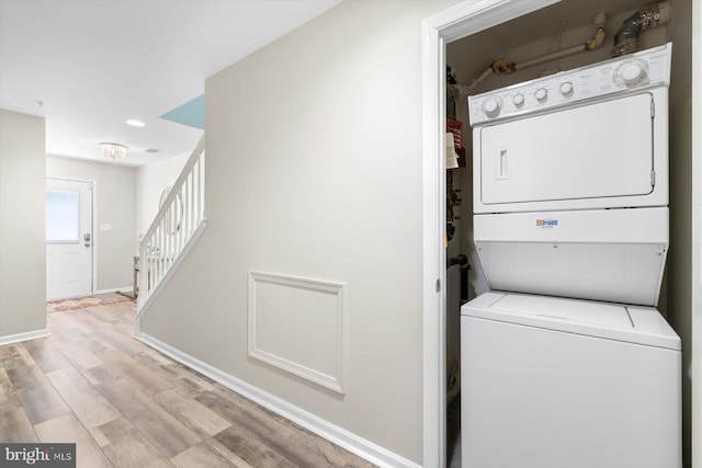 washroom featuring laundry area, light wood finished floors, recessed lighting, baseboards, and stacked washer and clothes dryer