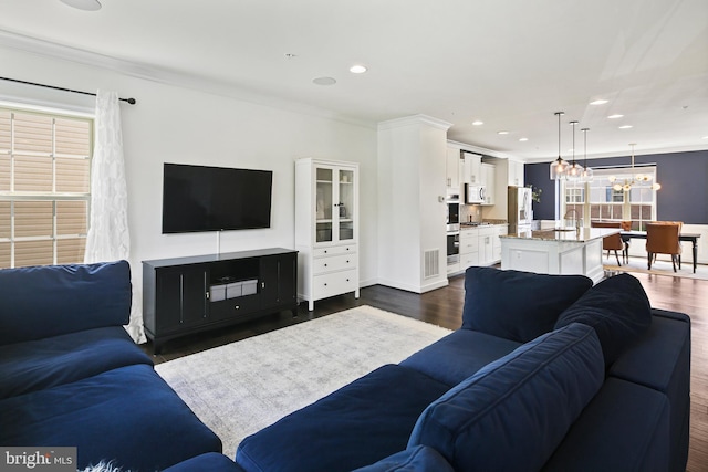 living area with crown molding, recessed lighting, dark wood finished floors, and a chandelier