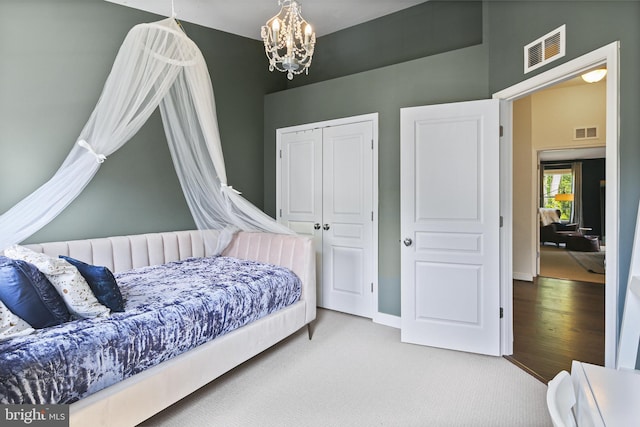 bedroom featuring carpet floors, visible vents, an inviting chandelier, and a closet