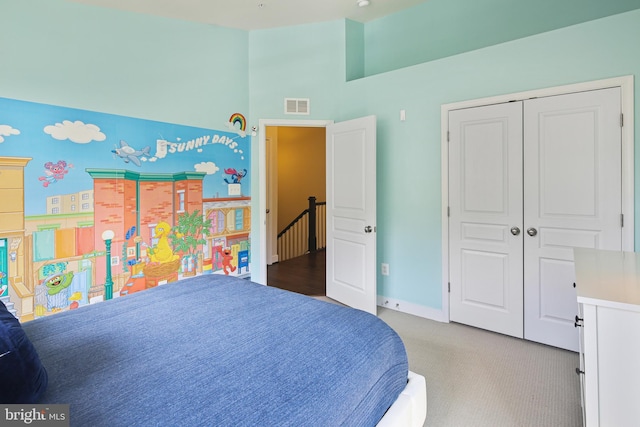 carpeted bedroom featuring baseboards, a high ceiling, a closet, and visible vents