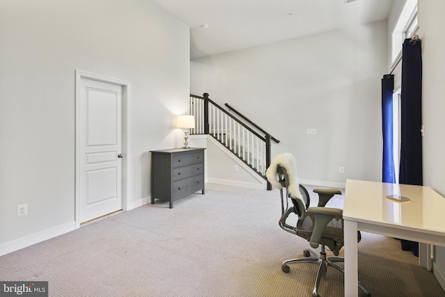 carpeted office space with baseboards and a towering ceiling