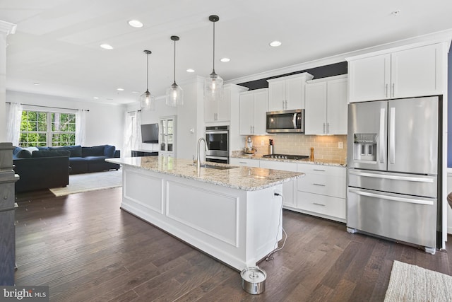 kitchen featuring white cabinets, open floor plan, appliances with stainless steel finishes, and a sink