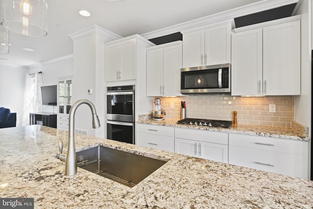 kitchen featuring crown molding, white cabinets, light stone countertops, a sink, and stainless steel appliances