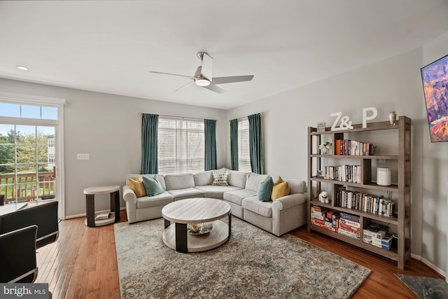 living room featuring baseboards, a ceiling fan, and wood finished floors