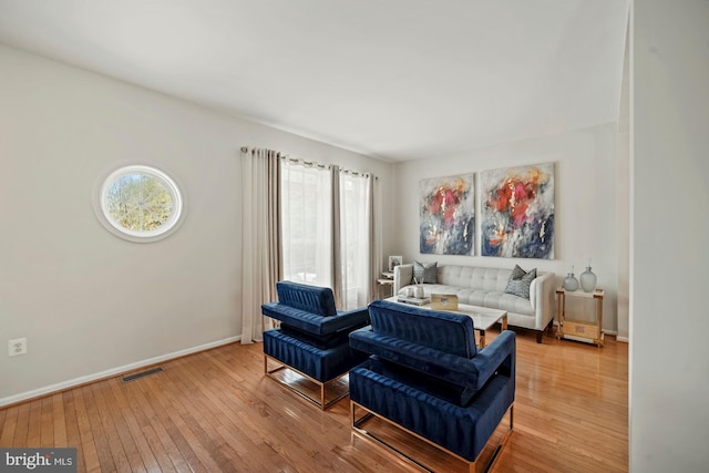 sitting room featuring light wood-style floors, visible vents, and baseboards