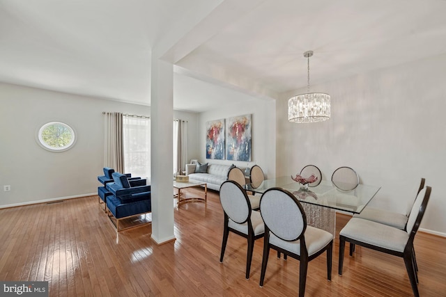 dining area featuring hardwood / wood-style flooring, an inviting chandelier, visible vents, and baseboards