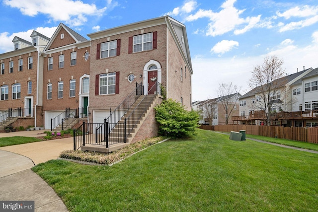 townhome / multi-family property with stairway, a residential view, an attached garage, driveway, and a front yard