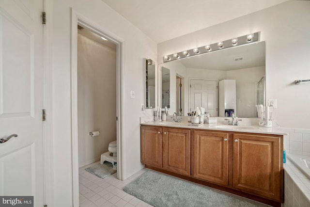 bathroom featuring tile patterned flooring, double vanity, toilet, and a sink