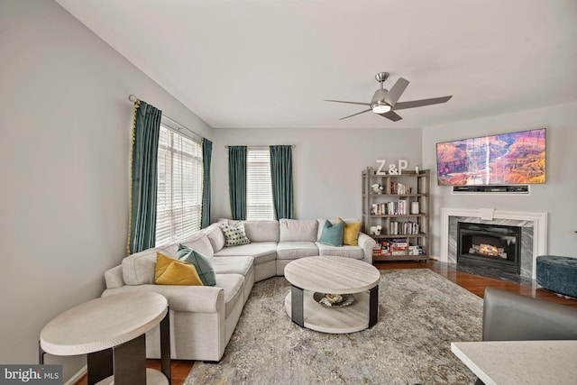 living area featuring a high end fireplace, wood finished floors, and a ceiling fan