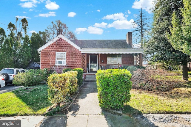 bungalow with a chimney, brick siding, roof with shingles, and covered porch