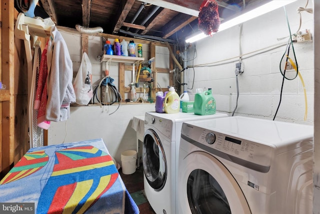 laundry area featuring concrete block wall, washer and clothes dryer, and laundry area