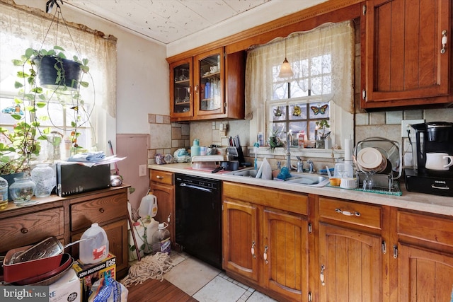 kitchen featuring dishwasher, brown cabinets, a sink, and light countertops