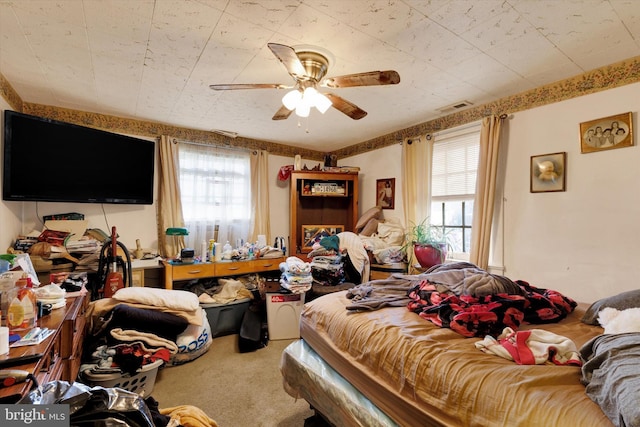 carpeted bedroom featuring visible vents, a ceiling fan, and multiple windows