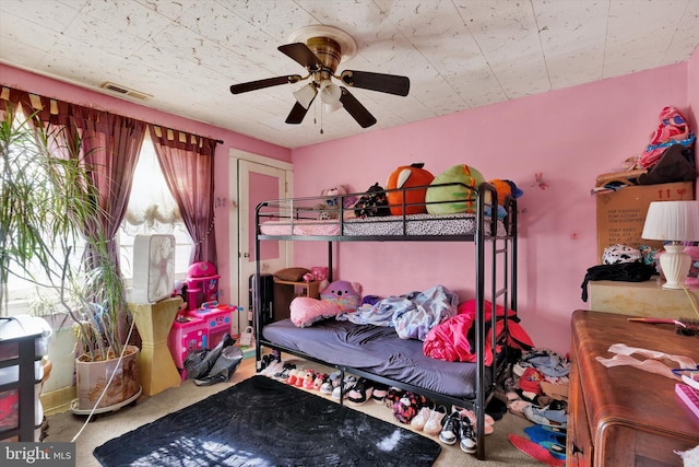 carpeted bedroom with a ceiling fan and visible vents