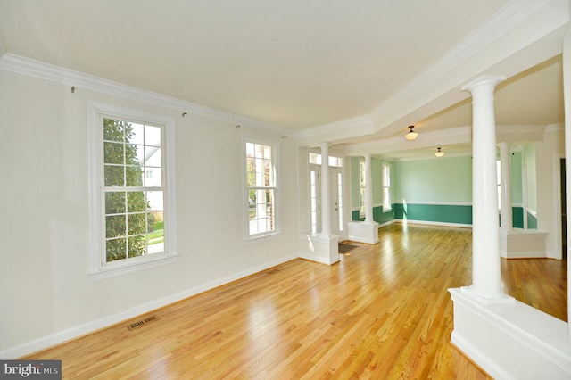 spare room with ornamental molding, light wood finished floors, visible vents, and decorative columns