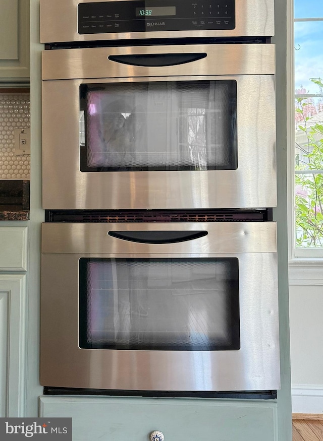 details featuring dark countertops, tasteful backsplash, and stainless steel double oven