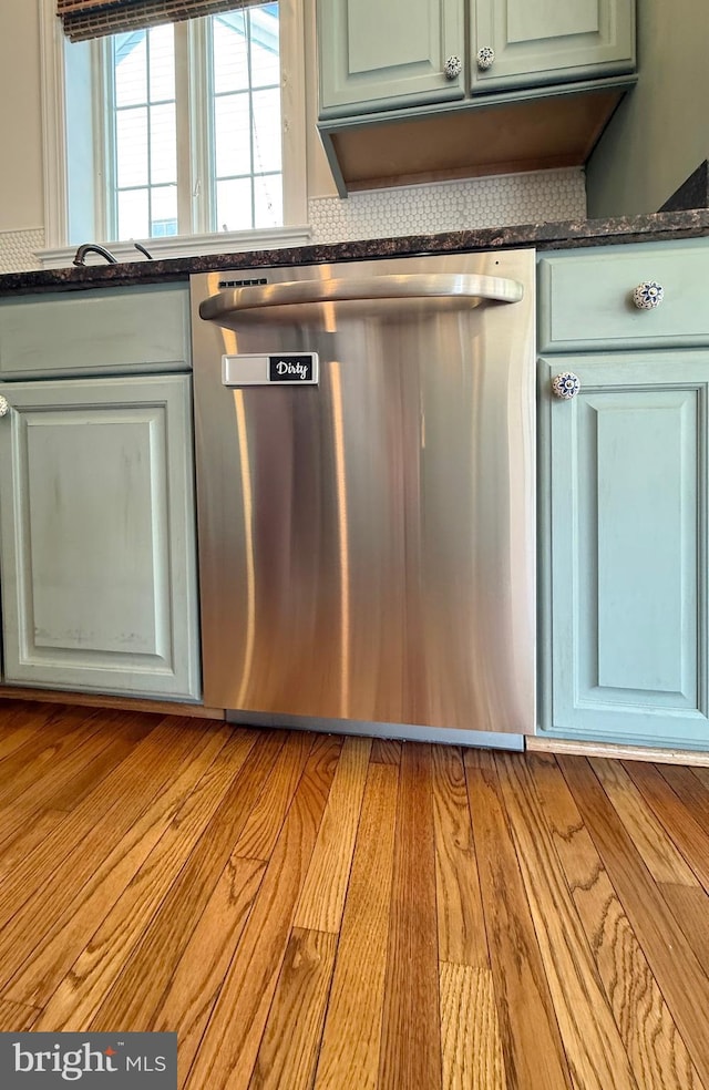 interior details with stainless steel dishwasher, dark countertops, and light wood-style flooring
