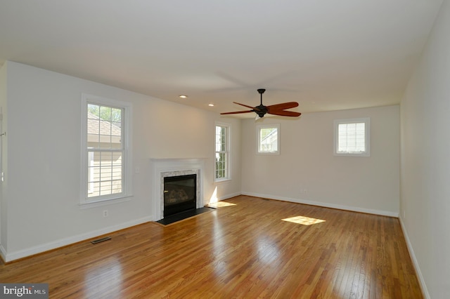 unfurnished living room featuring baseboards, visible vents, a wealth of natural light, and light wood-style floors