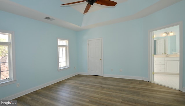 unfurnished bedroom featuring baseboards, visible vents, dark wood-style floors, and multiple windows