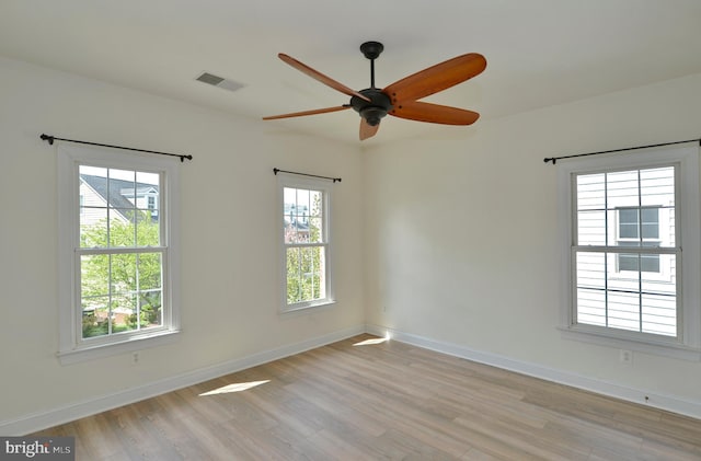 unfurnished room featuring light wood-style flooring, a wealth of natural light, and visible vents