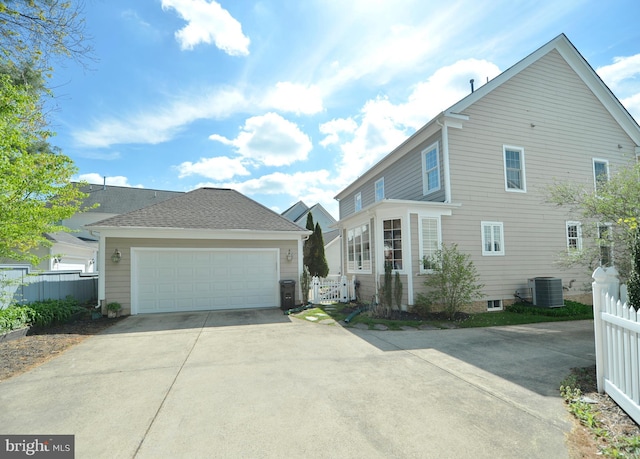view of front of house featuring central AC, fence, and a garage