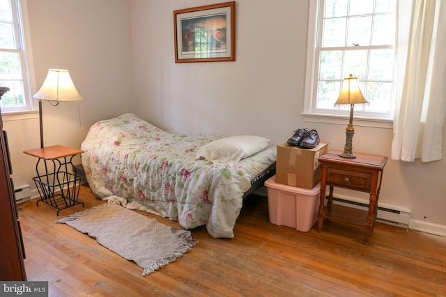 bedroom with a baseboard heating unit, baseboard heating, and wood finished floors