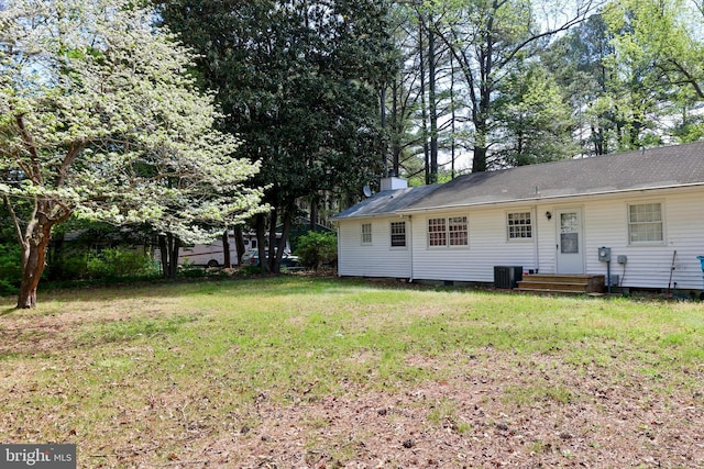 rear view of property with a yard, central air condition unit, crawl space, and a chimney