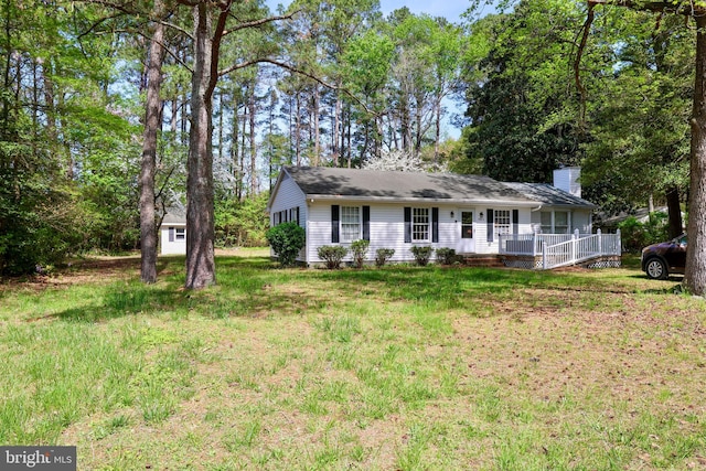 single story home with a front lawn, a wooden deck, and a chimney