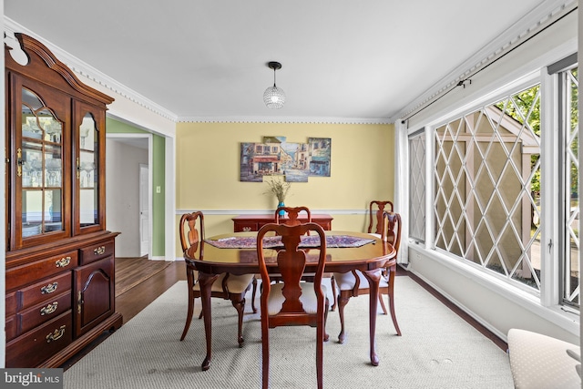 dining space featuring baseboards, wood finished floors, and ornamental molding