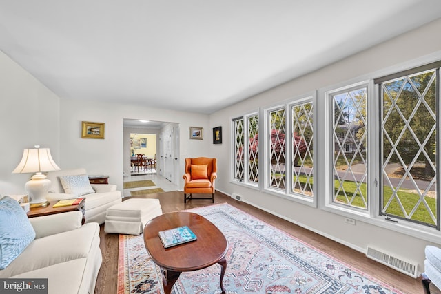 living area with baseboards, visible vents, and wood finished floors