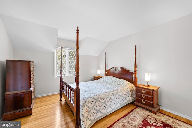 bedroom featuring baseboards, lofted ceiling, and light wood-style floors