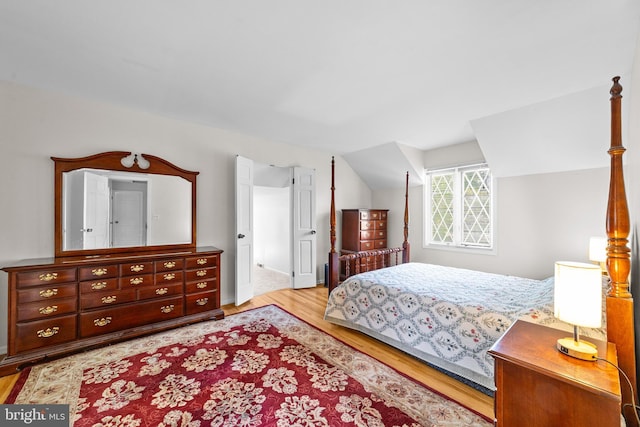 bedroom with light wood-style flooring and lofted ceiling
