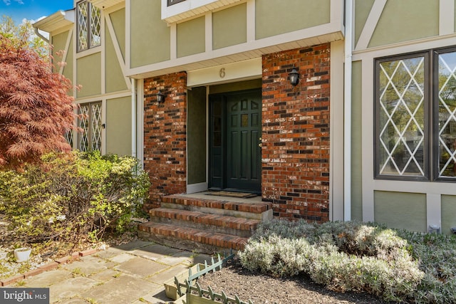 view of exterior entry featuring stucco siding and brick siding