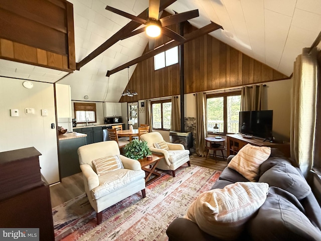 437 Orono Dr, Pocono Lake, PA 18347 - living area featuring beam ceiling, high vaulted ceiling, wood walls, a ceiling fan, and wood finished floors