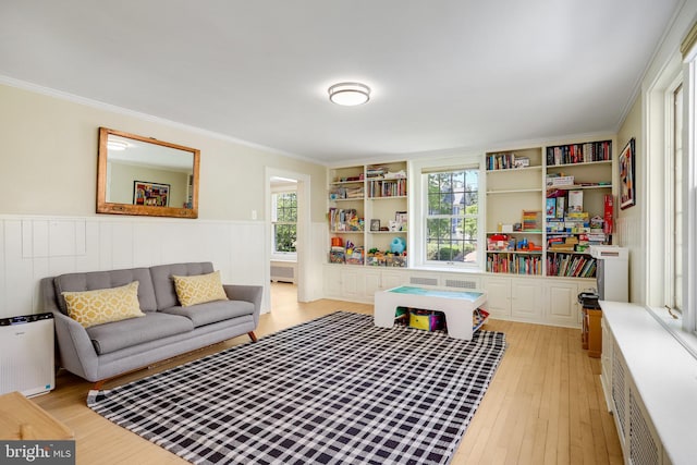 playroom featuring light wood-style floors, a wainscoted wall, plenty of natural light, and ornamental molding